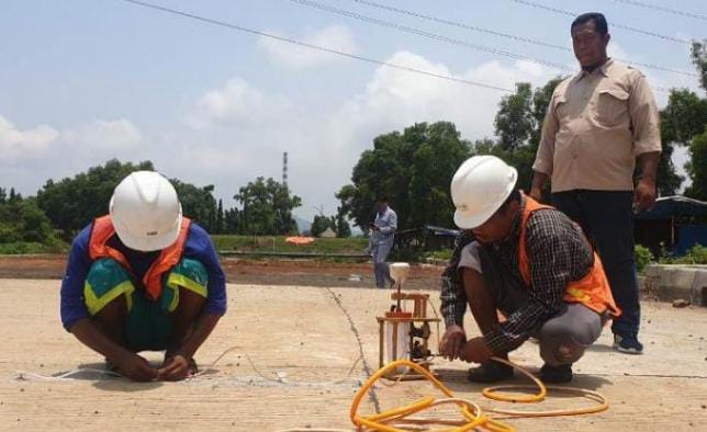 Pekerja PT Amarta Karya saat memperbaiki akses jalan beton Pelabuhan Warnasari yang mengalami retak rambu. (Foto: istimewah)