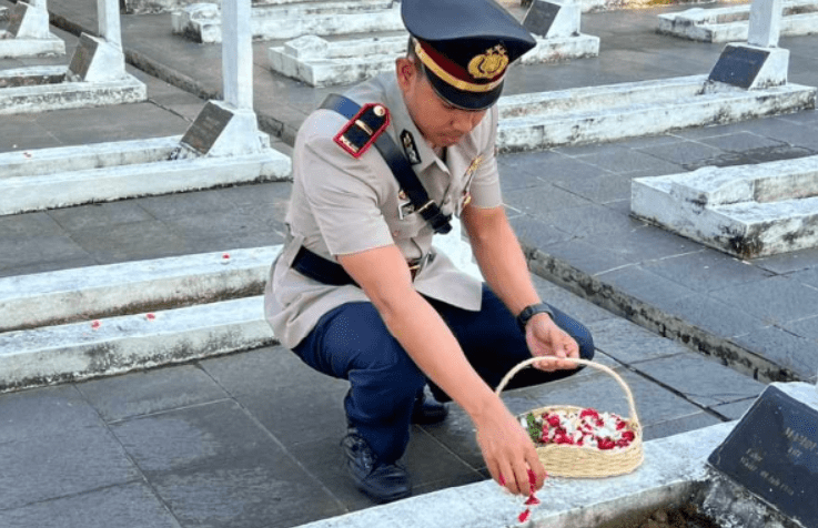 Salah satu anggota Satlantas Polres Karawang IPDA Ega menaburkan bunga di taman makam pahlawan. (Foto: Fathar)